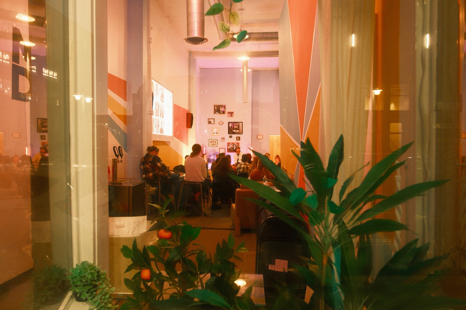 View through the front window of The Clubhouse at 318 N Milwaukee St in Milwaukee's Historic Third Ward, showing a full room of MKE DMC attendees facing the panel on AEO, GEO, and SEO