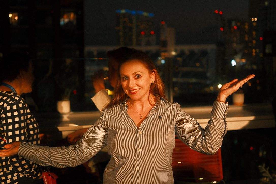 A guest in a striped shirt gestures toward the San Diego skyline at night during SERP & TURF