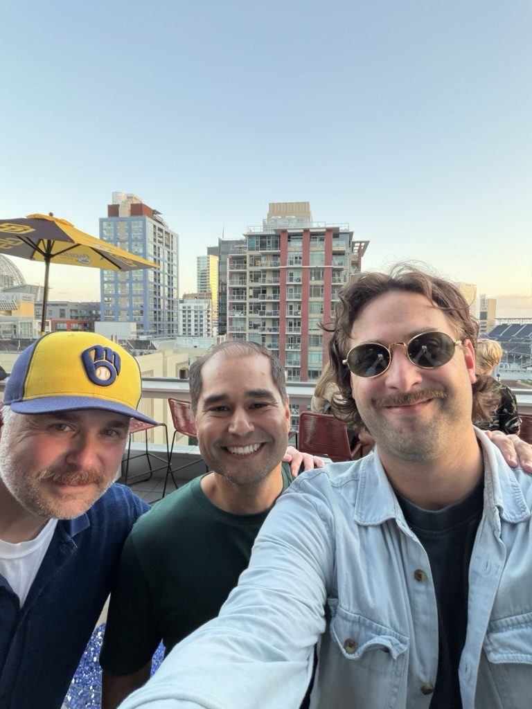 Rooftop selfie at SERP & TURF in downtown San Diego: from left, Momentic cofounder Tony Van Sant in a Milwaukee Brewers cap, Previsible CEO Jordan Koene, and Momentic cofounder Tyler Einberger
